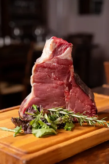 Bistecca alla fiorentina cruda su tagliere di legno